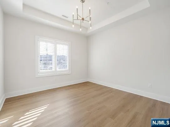 an empty room with a chandelier fan and windows