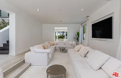 a living room with furniture a flat screen tv and a window