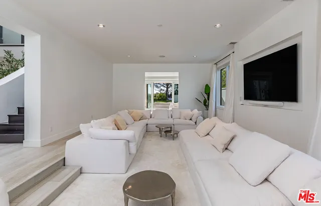 a living room with furniture a flat screen tv and a window