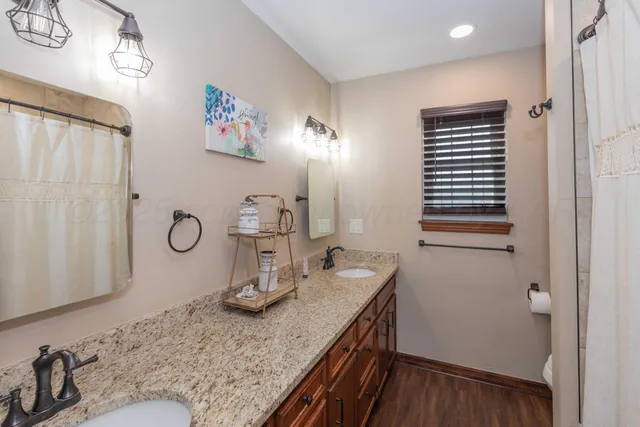 a bathroom with a granite countertop sink a mirror and shower