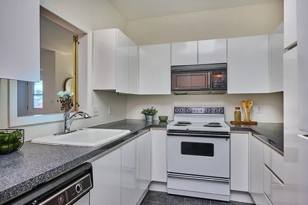 a kitchen with granite countertop a sink a stove and cabinets