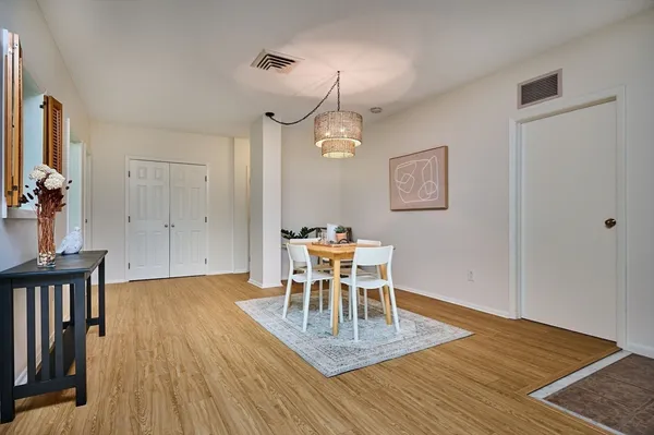 a dining room with wooden floor a chandelier a wooden table and chairs