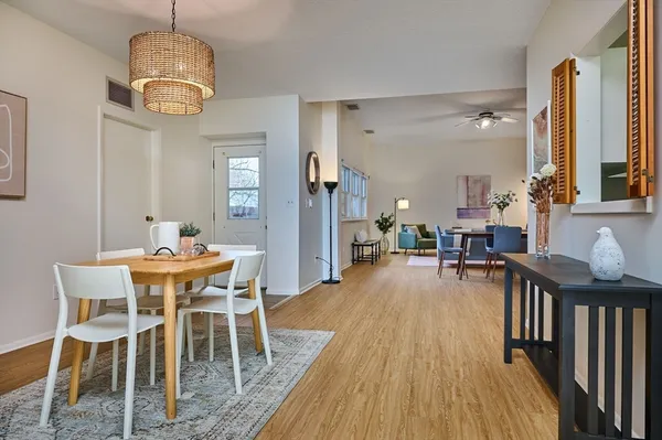 a dining room with wooden floor a chandelier a wooden table and chairs