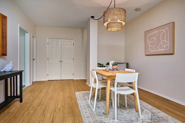 a dining room with wooden floor a chandelier a wooden table and chairs