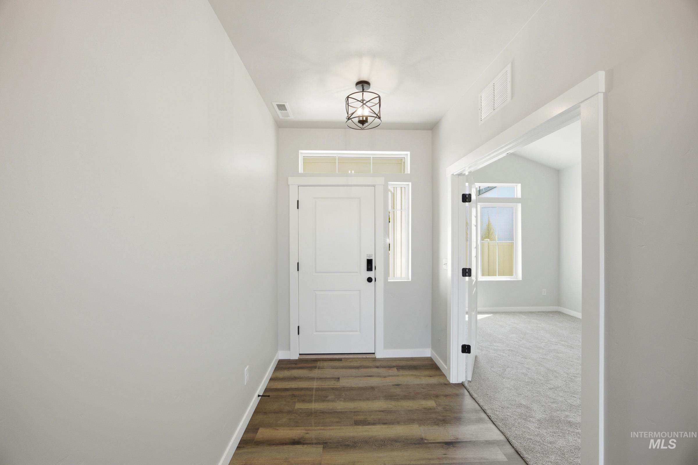 4344 East Rincon Drive Meridian, ID 83642 - Photo 2 of 26 Entryway with wood-finish flooring, a contemporary ceiling fixture, and a white paneled door with transom window