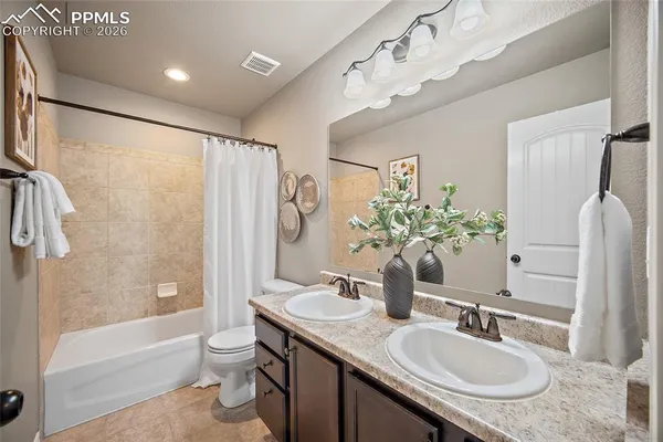 a bathroom with a granite countertop sink a toilet a mirror a bathtub and shower