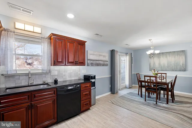 a kitchen with granite countertop a sink dishwasher a dining table and chairs with wooden floor