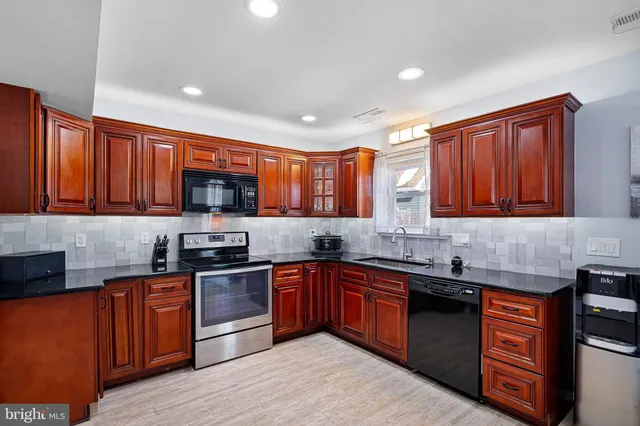 a kitchen with stainless steel appliances granite countertop wooden cabinets a sink and dishwasher a stove top oven with wooden floor