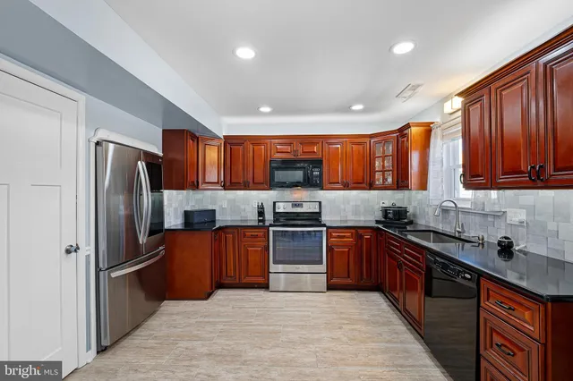 a large kitchen with stainless steel appliances granite countertop a refrigerator a sink a stove top oven and a center island