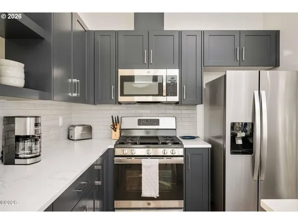 a kitchen with stainless steel appliances a stove a microwave a sink and cabinets