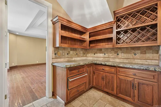 a large white kitchen with granite countertop a large window sink and cabinets