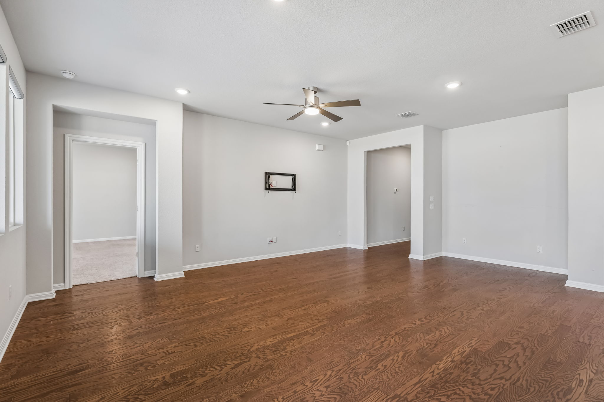 Rich hardwood floors anchor this open room featuring clean-lined doorways and recessed lighting.