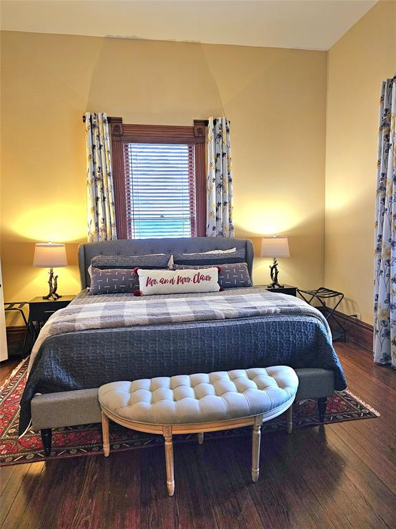 1111 West Main Street Denison, TX 75020 - Photo 13 of 36 a room with a bed a mirror and wooden floor