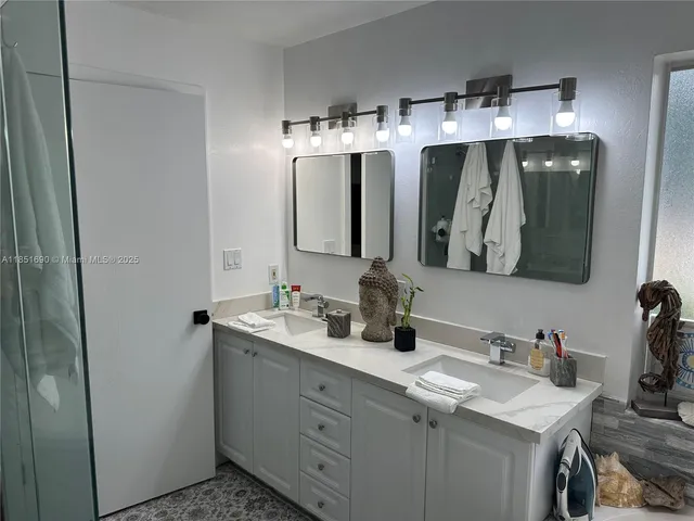a en suite bathroom with a double vanity sink a mirror and shower
