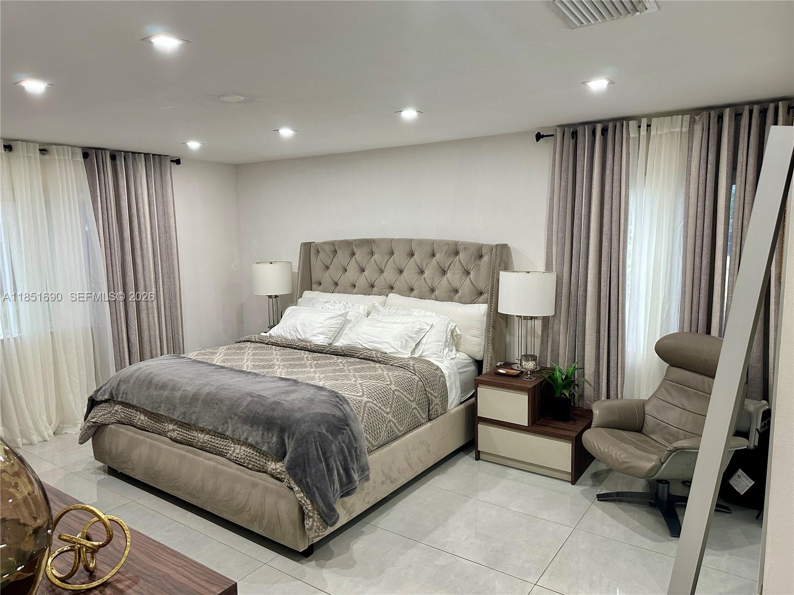 11 Northeast 151st Street Miami, FL 33162 - Photo 26 of 95 a spacious bedroom with a bed and glass window
