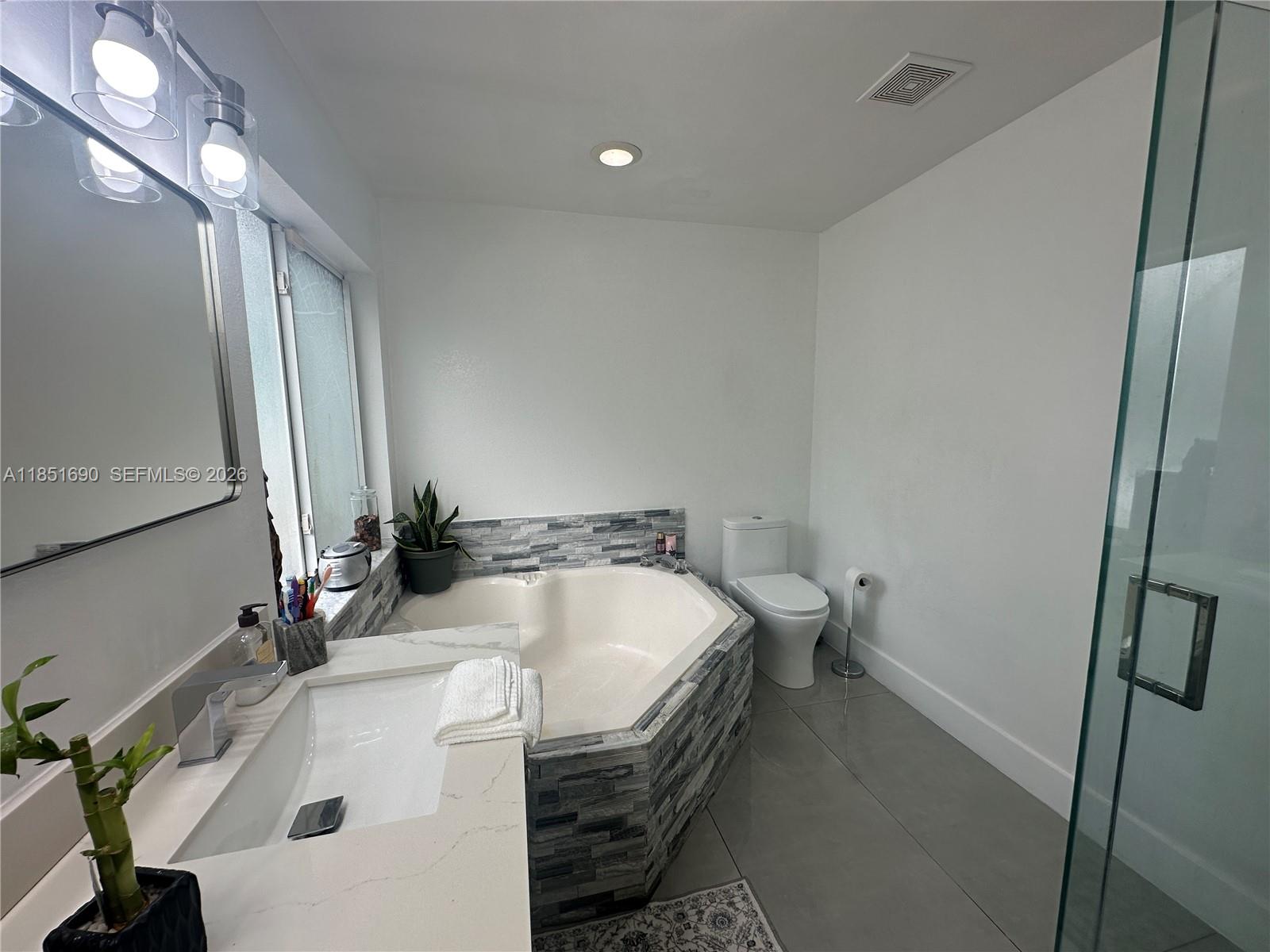 11 Northeast 151st Street Miami, FL 33162 - Photo 34 of 95 a bathroom with a sink a toilet and a mirror
