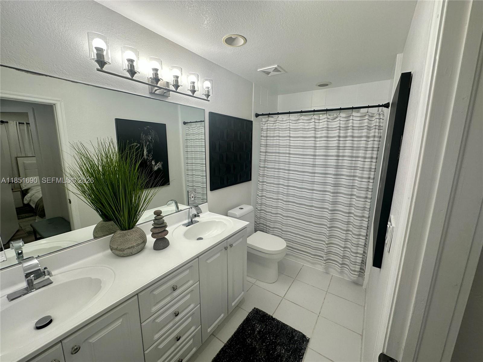 11 Northeast 151st Street Miami, FL 33162 - Photo 80 of 95 a bathroom with a sink a toilet a mirror and shower