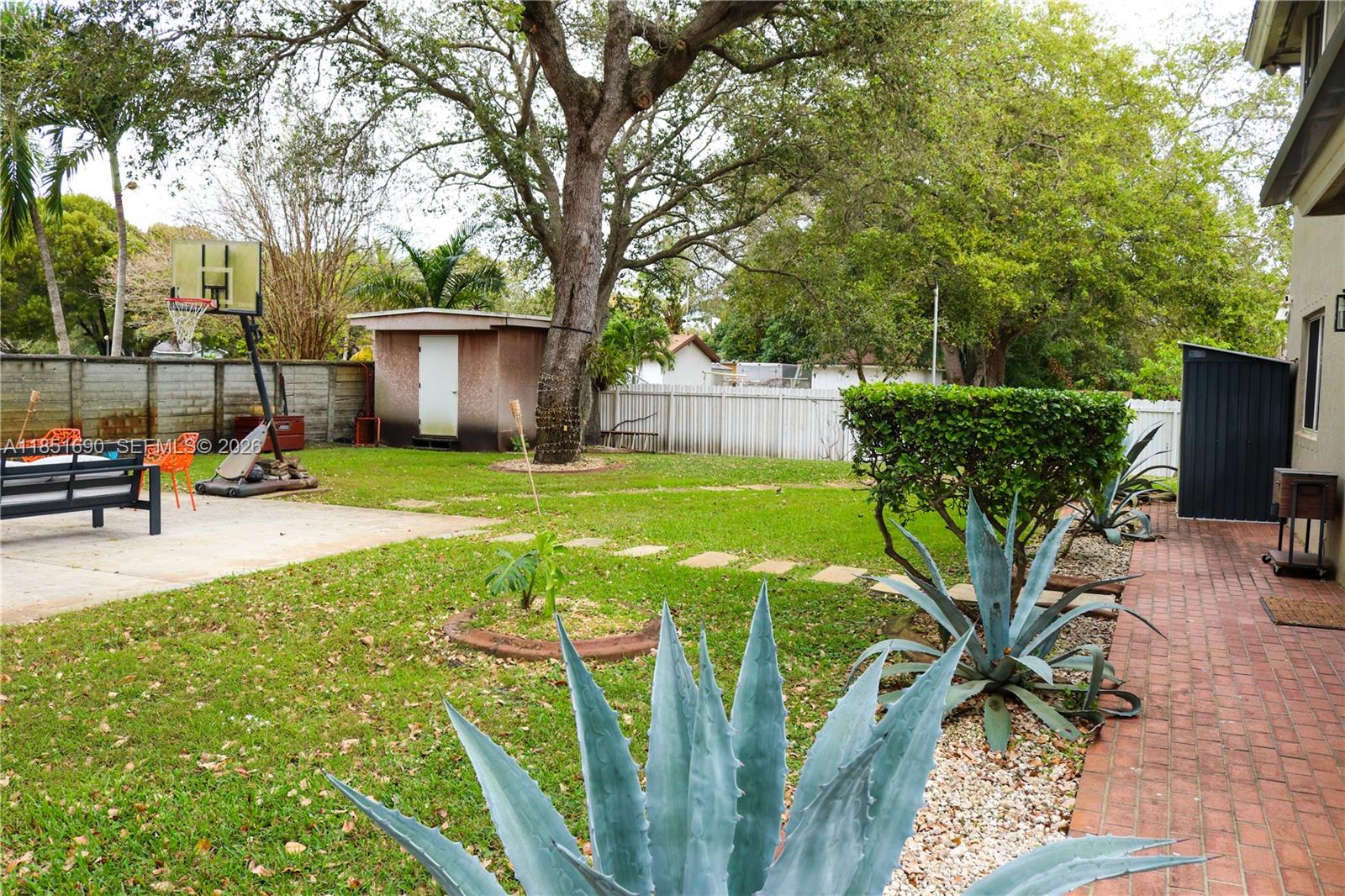 11 Northeast 151st Street Miami, FL 33162 - Photo 87 of 95 a view of a backyard with table and chairs potted plants and large tree