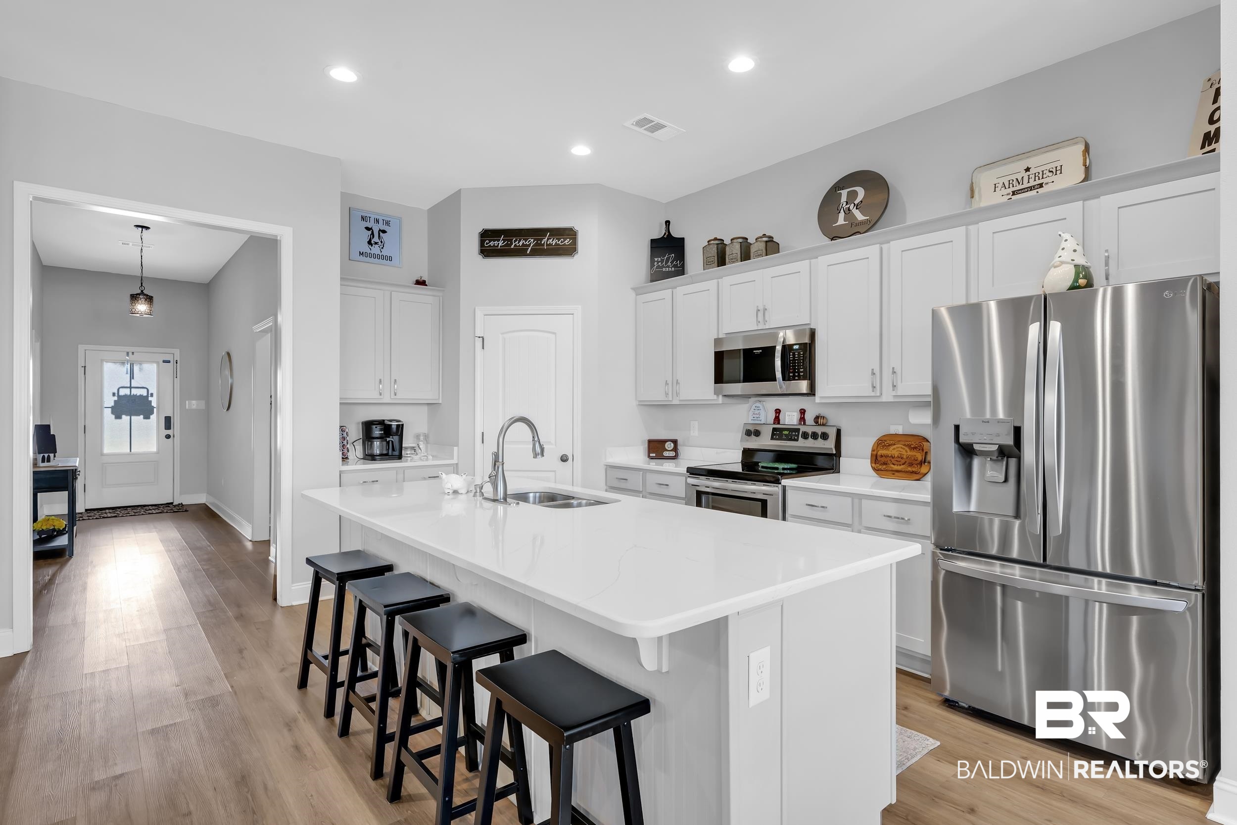 1176 Stella Road Foley, AL 36535 - Photo 12 of 40 Kitchen featuring stainless steel appliances, white cabinetry, a kitchen breakfast bar, a center island with sink, and light wood-style floors