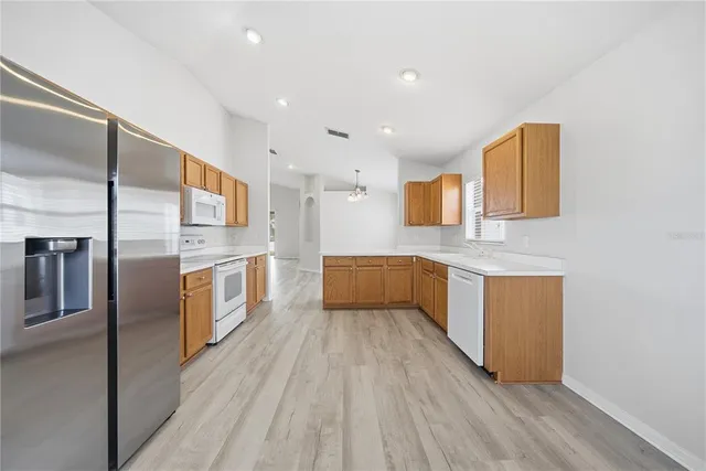 a large white kitchen with stainless steel appliances a sink and a large window
