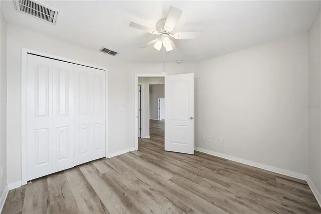 an empty room with wooden floor and a ceiling fan