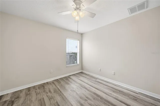 an empty room with a chandelier fan and windows