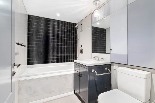 a bathroom with a granite countertop toilet sink and mirror