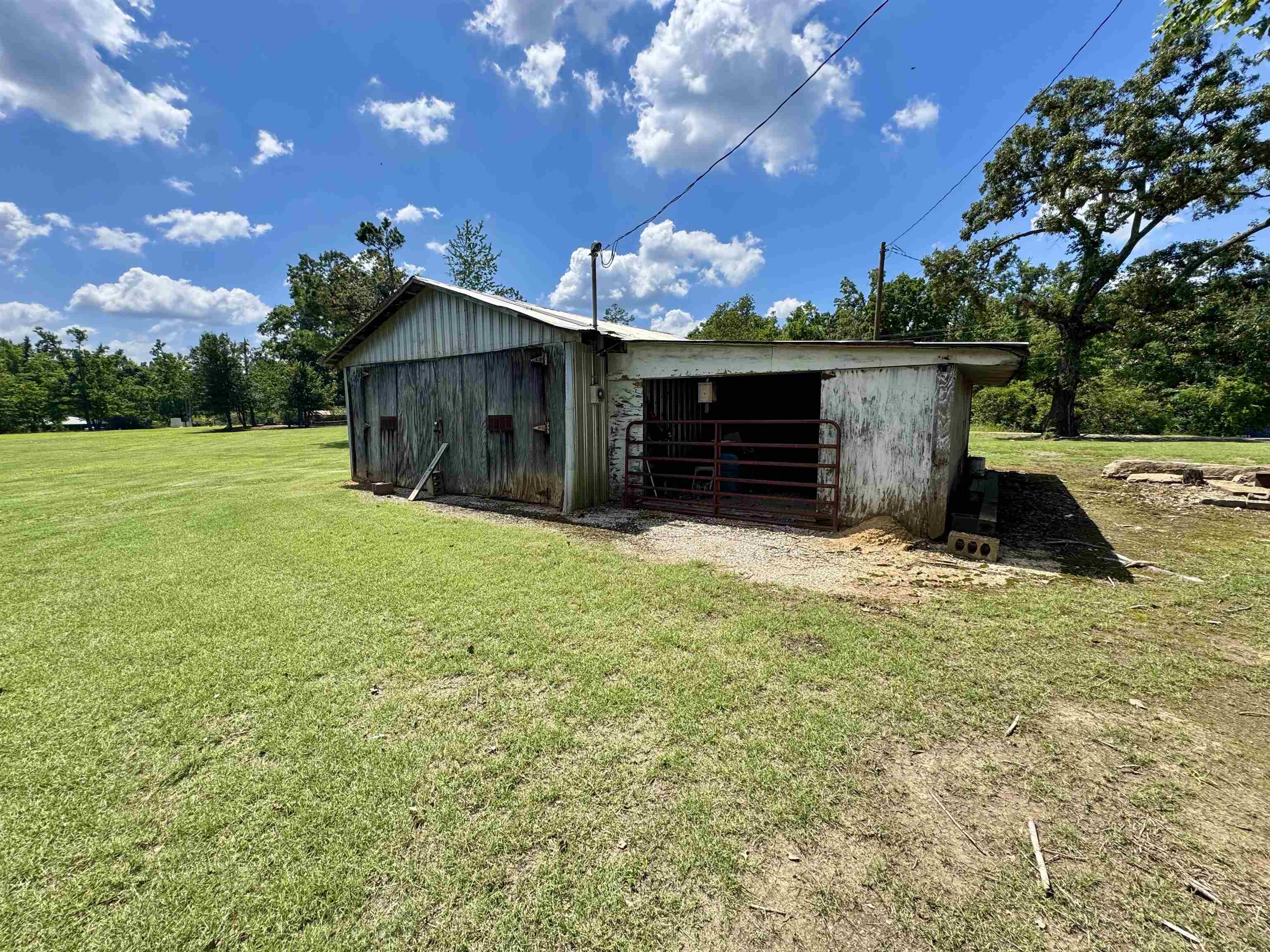 2511 Watkins Road Michie, TN 38357 - Photo 10 of 40 Metal-sided outbuilding featuring an attached open-sided lean-to structure with metal gating, positioned on a gravel and dirt foundation