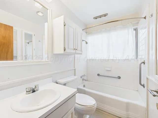 an empty room with windows fireplace and a kitchen view
