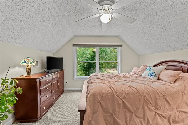a bedroom with a bed and a flat tv screen on dresser