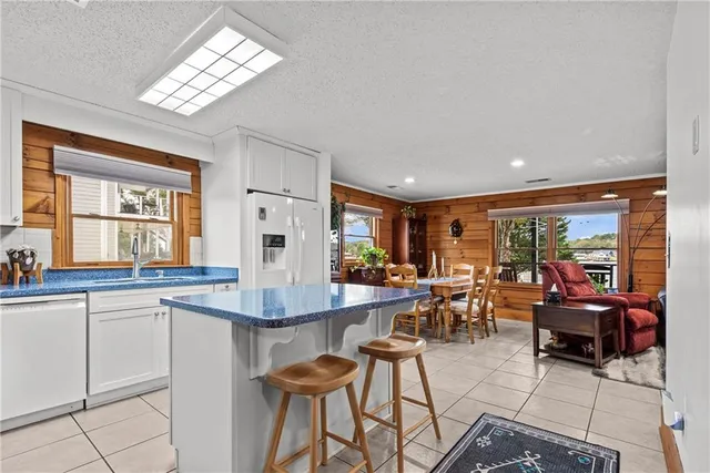 a very nice looking dining room with kitchen island furniture a chandelier a large window and kitchen view
