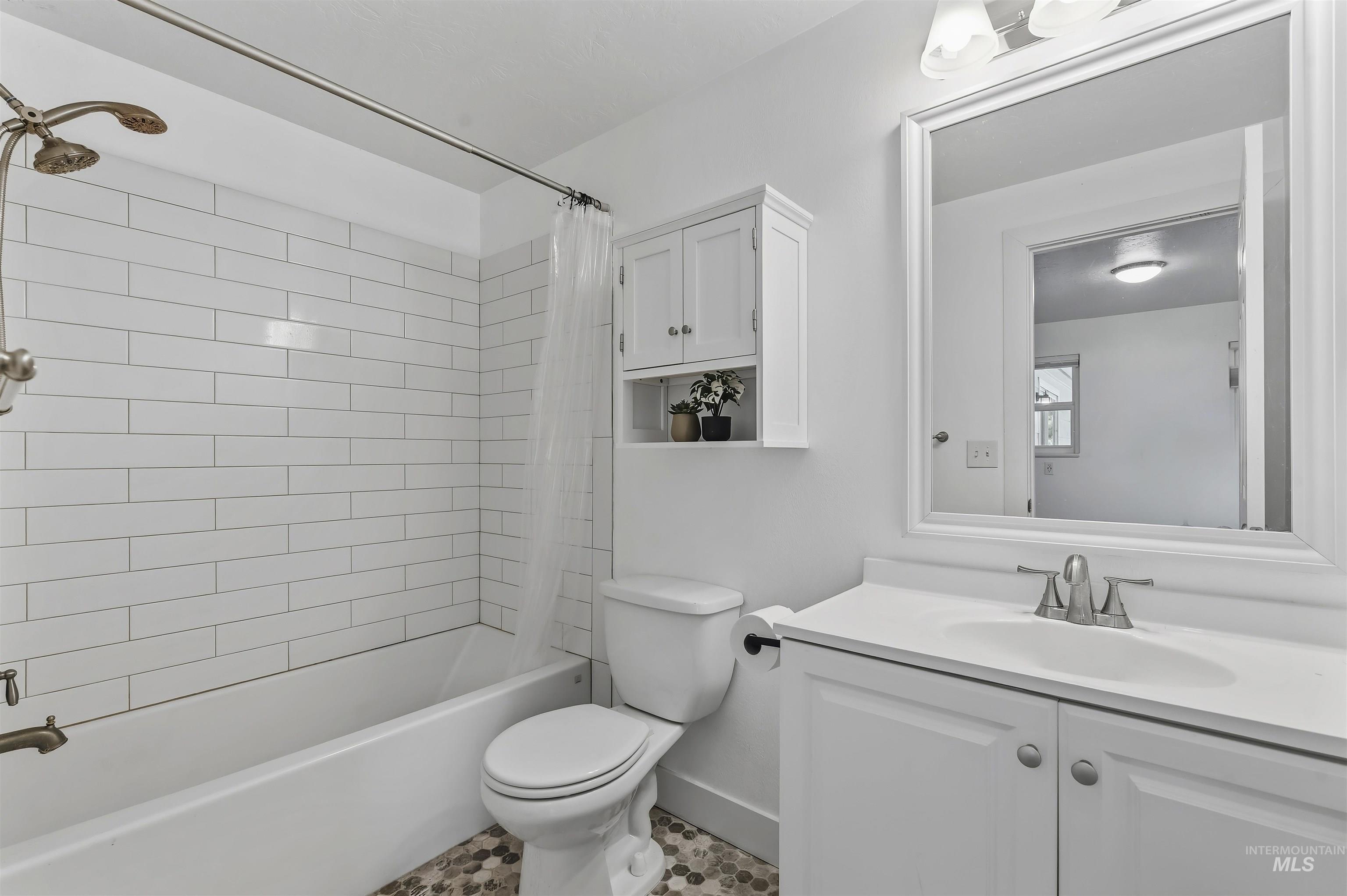 355 East Beacon Light Road Eagle, ID 83616 - Photo 16 of 47 Bathroom featuring a white subway tile shower surround, a built-in white cabinet with open shelving, a white vanity with an integrated sink, a framed mirror, and mosaic tile flooring