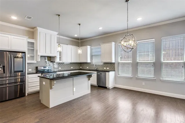a large kitchen with lots of counter space wooden floor and stainless steel appliances