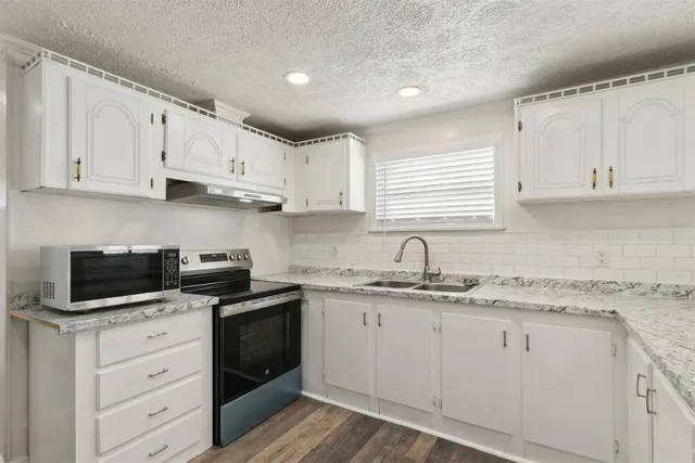 a kitchen with cabinets appliances a sink and a window