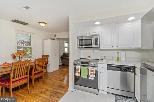 a open kitchen with stainless steel appliances granite countertop a stove top oven a sink a table and chairs