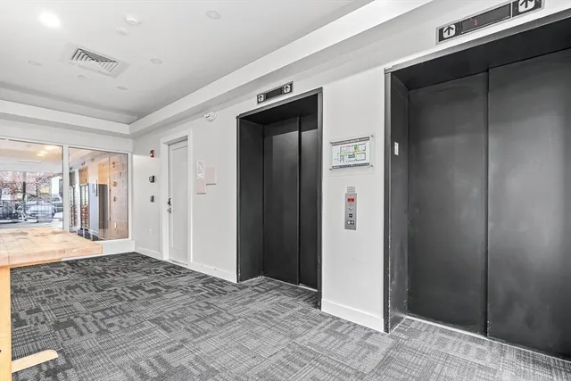 a view of a hallway with wooden floor and a bathroom