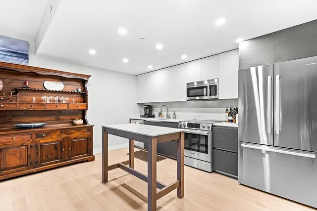 a kitchen with stainless steel appliances granite countertop a stove top oven a sink and a refrigerator