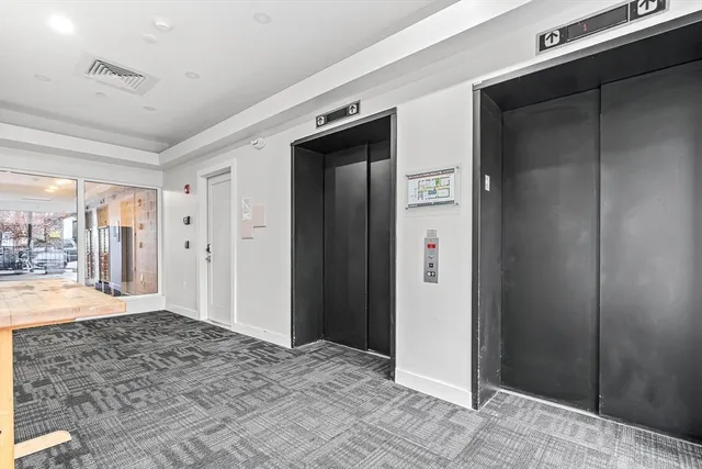 a view of a hallway with wooden floor and a bathroom