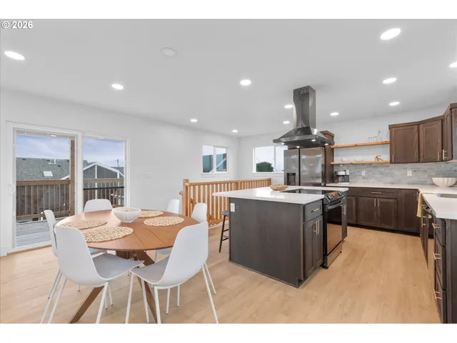 a kitchen with a table chairs a sink dishwasher a stove and a dining table with wooden floor