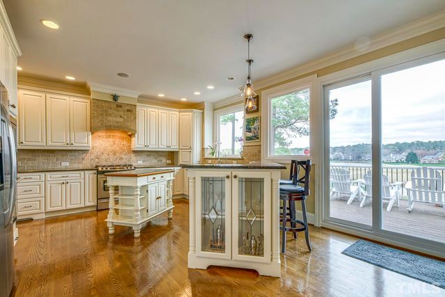 a kitchen with stainless steel appliances granite countertop a stove top oven a sink with island and chairs