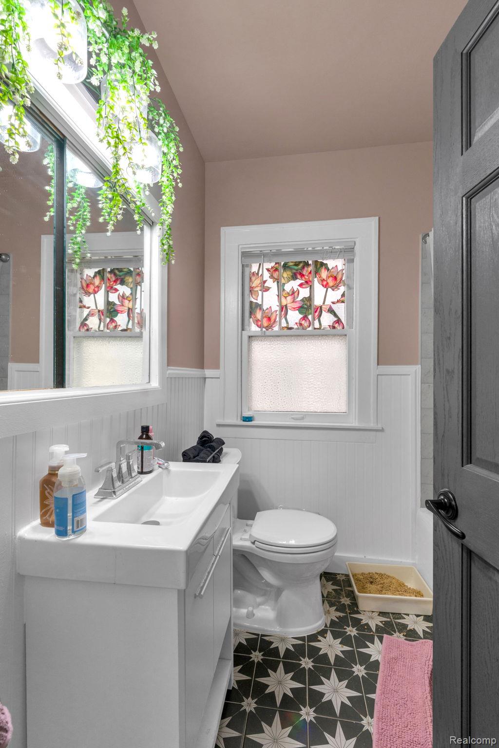 7631 Maple Street Dearborn, MI 48126 - Photo 23 of 48 Bathroom featuring a single vanity, white board and batten wall paneling, and star-patterned floor tiling