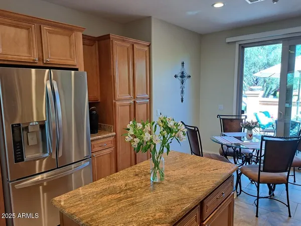 a kitchen with stainless steel appliances granite countertop a dining table chairs and a refrigerator