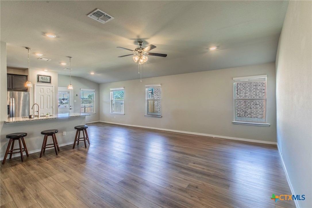a view of an empty room with wooden floor and a ceiling fan