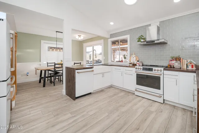 a kitchen with a stove a sink and white cabinets with wooden floor
