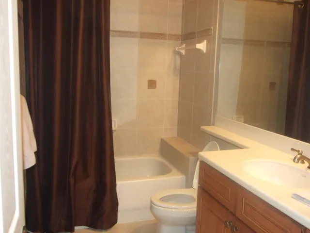 a bathroom with a granite countertop bathtub shower sink vanity and toilet