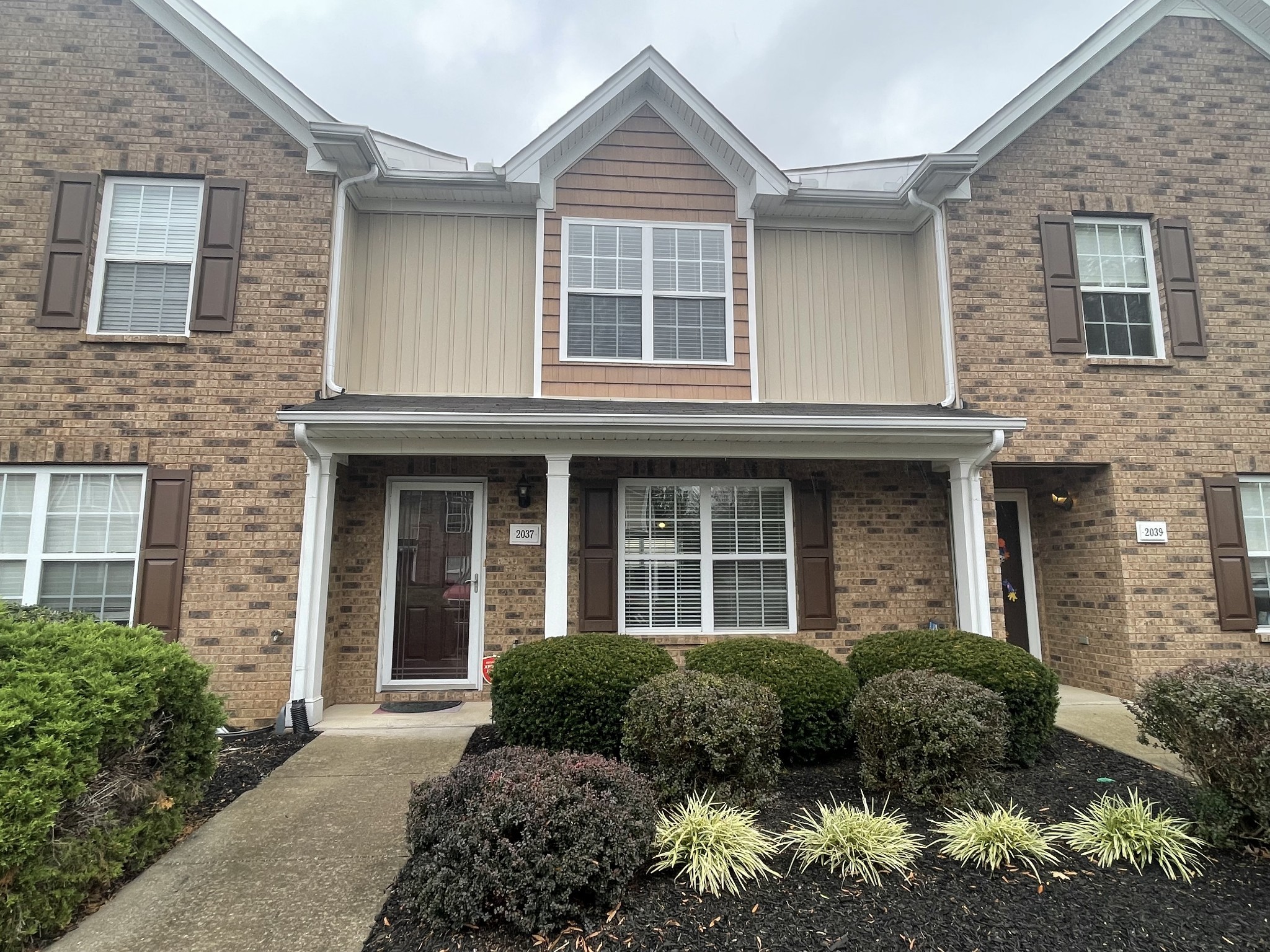 a view of a brick house with plants and large windows