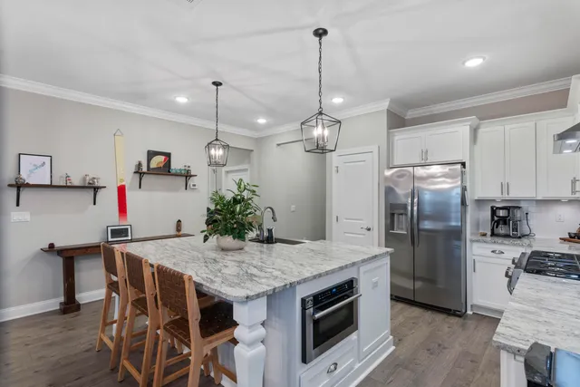a kitchen with granite countertop a table chairs stainless steel appliances and wooden floor