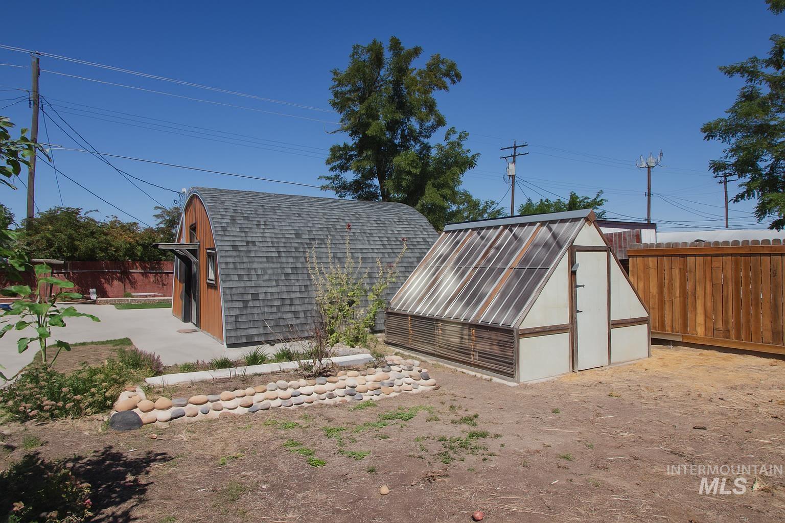 161 Southeast 5th Avenue Ontario, OR 97914 - Photo 24 of 41 Rear view of house featuring a Quonset hut, a fenced backyard, and a greenhouse
