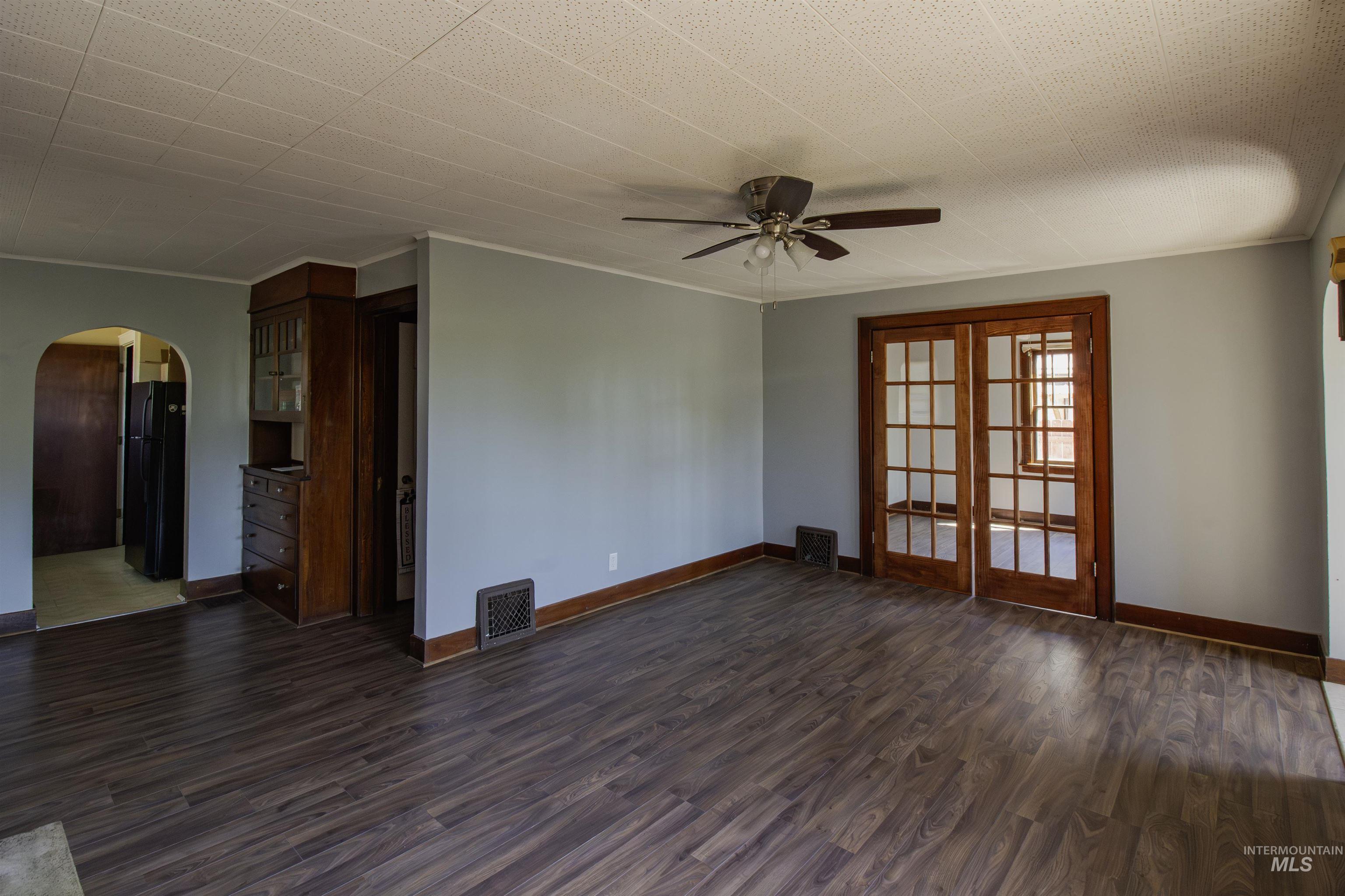 161 Southeast 5th Avenue Ontario, OR 97914 - Photo 40 of 41 Empty room with arched walkways, dark wood-type flooring, a ceiling fan, and ornamental molding