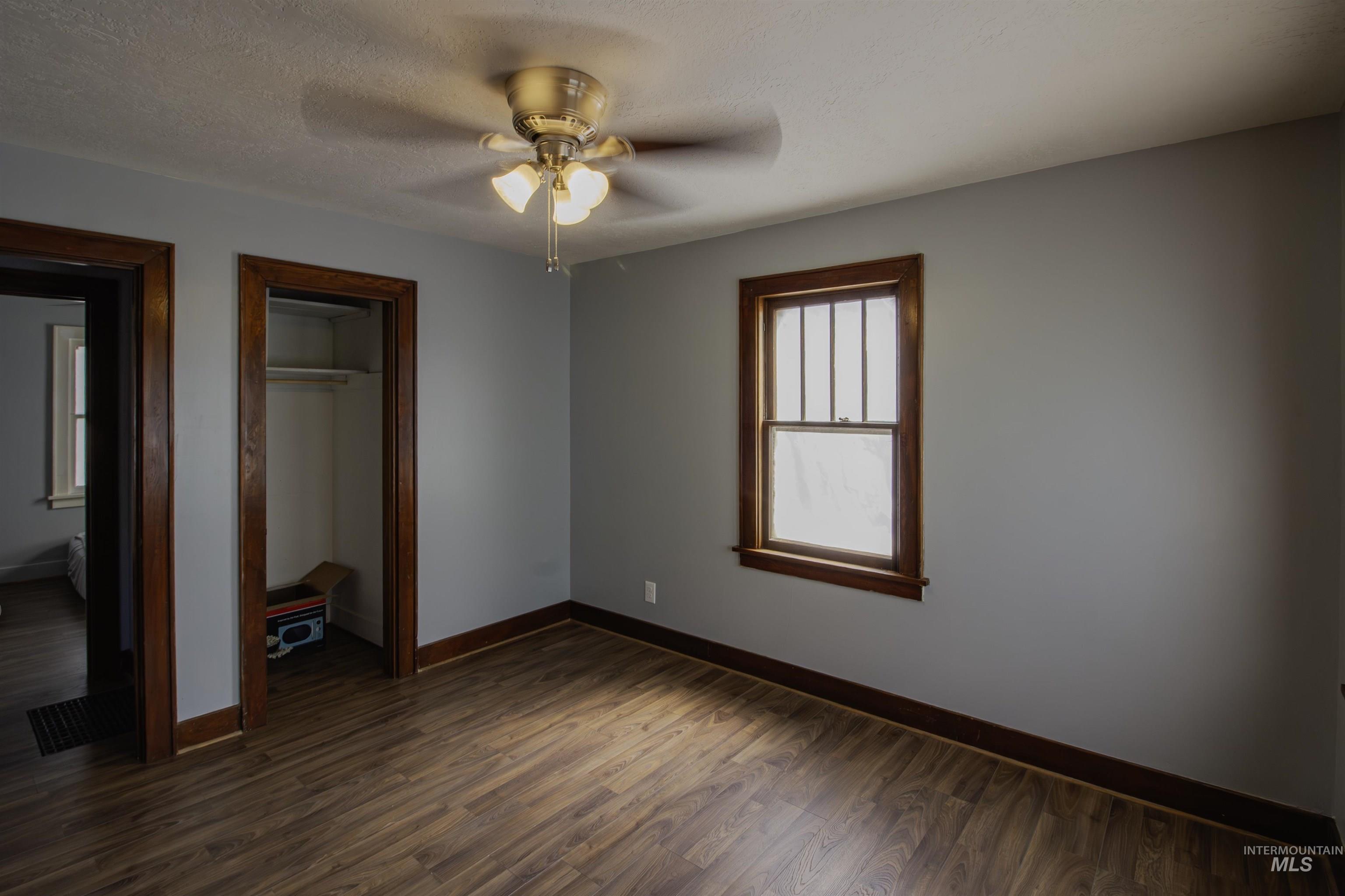 161 Southeast 5th Avenue Ontario, OR 97914 - Photo 10 of 41 Unfurnished bedroom with dark wood-style floors, a closet, a textured ceiling, and ceiling fan